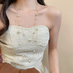 Close-up of double-layer gold pearl necklace with various bead sizes on elegant model