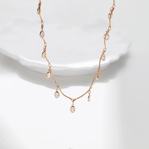 Detail of 18K gold plated wavy chain necklace with oval cubic zirconia charms