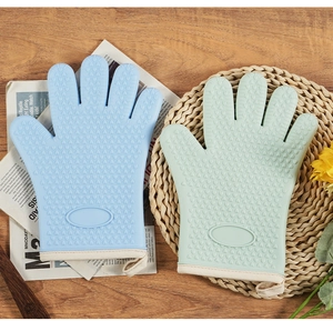 Silicone oven mitts in blue and green with heart texture on a wooden table with decor