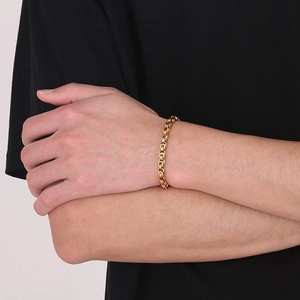 Gros plan d'un bracelet byzantin plaqué or porté par un mannequin dans un style minimal