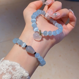 Detail of light blue cat eye stone beaded bracelets with heart and teardrop charms