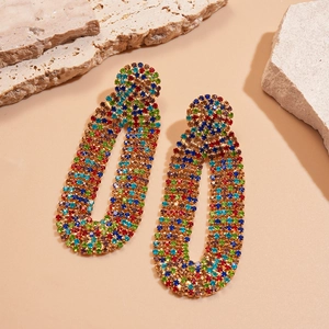Macro shot of long oval drop earrings with vibrant multi-colored rhinestones on beige stone