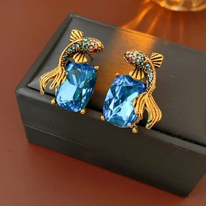 Detail of vintage koi fish earrings with blue gemstones and colorful rhinestones