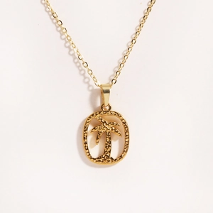 Macro shot of gold oval pendant with hollow coconut tree detail on stainless steel chain