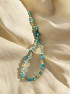 Detailed macro view of glacier blue cat eye beads and golden cylindrical spacers