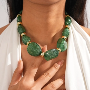 Detail of green glitter acrylic beads and gold metal spacers on an irregular necklace