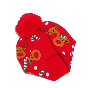 Detail of red Christmas knit hat featuring reindeer and candy cane patterns with pom-pom