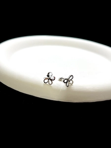 Detailed view of silver hollow flower stud earrings with secure screw back ball on white plate