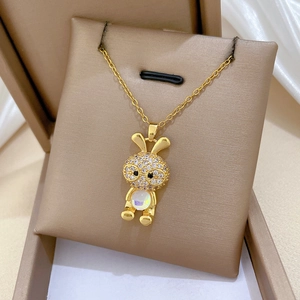 Close-up of golden bunny pendant with clear zircons and round opal stone on an O-chain