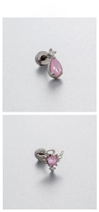 Détail macro de clous d'oreilles en titane avec cœurs en zircon rose et ailes