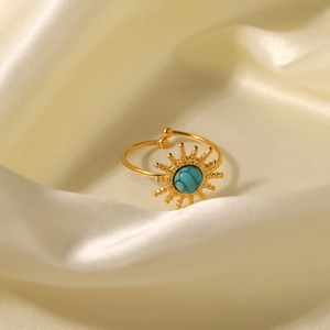 Detailed shot of golden sunburst ring featuring a round turquoise stone on beige silk