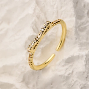 Elegant gold bow cubic zirconia adjustable ring on a natural stone background