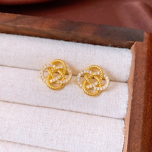 Macro shot of gold-plated twisted knot earrings with micro-paved zircons on linen