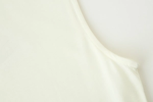 Gros plan détaillé sur la texture du coton beige et les coutures précises de la robe