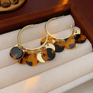 Gold round hoop earrings with leopard print tortoiseshell tassels on velvet jewelry box