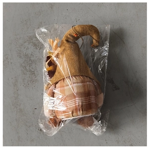 Macro shot of fall gnome doll in polybag with plaid body and burlap scarecrow hat