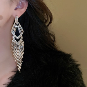 Close-up of model wearing long gold tassel earrings with sparkling rhinestone fringe