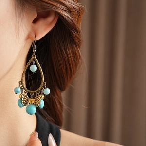 Detail of vintage bohemian drop earrings with turquoise beads and gold discs on model
