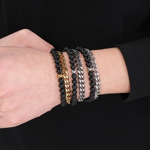 Close-up of stacked black agate beads and gold silver cuban chain bracelets on wrist