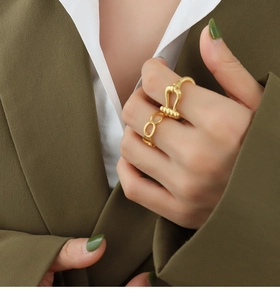 Close-up of gold horseshoe and chain link rings worn on fingers with a green blazer