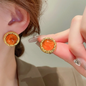 Detail of vintage round amber resin earrings with golden quilted texture metal frame