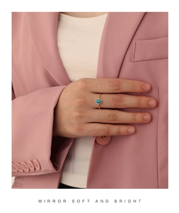 Detail of bohemian gold ring with oval turquoise stone worn on model hand