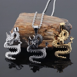 Three Chinese dragon pendants in gold, silver, and black finishes on natural rock surface