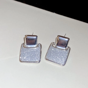 Detail of silver square stud earrings featuring a sparkling glitter inlay and polished finish
