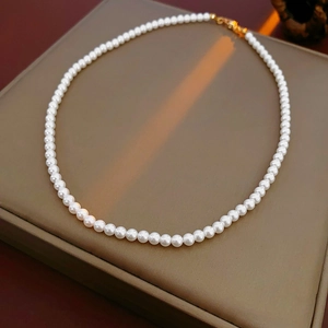 Détail d'un collier de perles blanches élégantes avec fermoir doré sur un coussin à bijoux