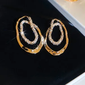 Gold plated irregular double hoop earrings with sparkling rhinestones on black velvet
