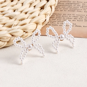 Macro detail of handmade pearl bow earrings on a vintage aesthetic background
