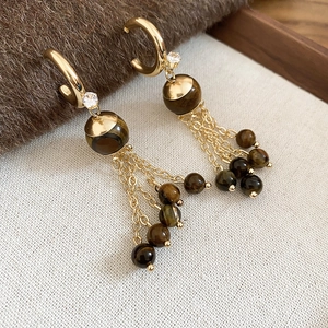 Detailed macro view of vintage golden tassel earrings with tiger eye beads and zircon