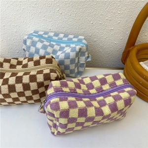 Close-up of knitted checkerboard cosmetic bags in blue, brown and purple with zippers