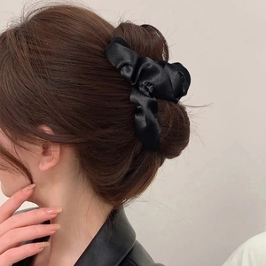 Elegante pinza per capelli in raso nero con design a fiocco pieghettato indossata da una modella