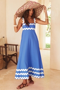 Close-up of blue maxi dress showing elegant white wave trim on neckline and straps