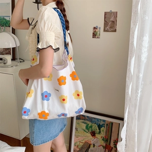 Detailed side view of large canvas tote bag with floral print worn by a model