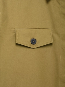 Close-up of mustard yellow shirt showing flap pocket detail and a dark button fastener