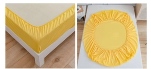 Detail of bright yellow fitted sheet with elastic band showing secure fit on mattress corner