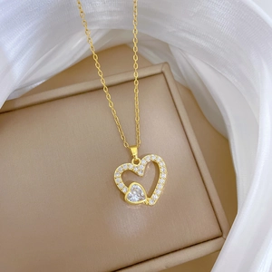 Détail du pendentif cœur doré serti de cristaux brillants sur de la soie blanche