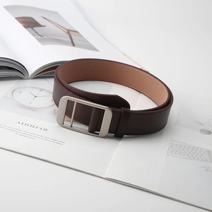 Detailed macro shot of dark brown leather belt with matte silver buckle on magazine