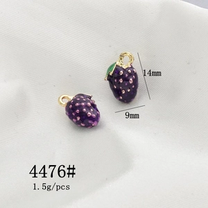 Detail view of purple enamel strawberry charms with dimensions 14mm by 9mm and gold alloy finish