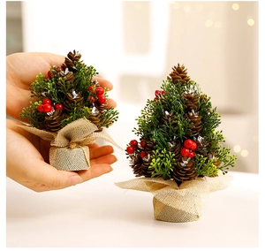 Close-up of mini Christmas trees with red berries and burlap base in warm bokeh lighting