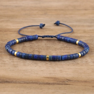 Detailed macro shot of blue imperial stone beads and gold cylinder spacers on woven cord