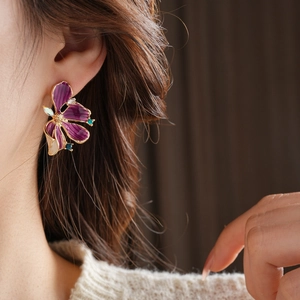 Detailansicht der Vintage lila Blumenohrringe mit Goldrand und Kristallen am Modell