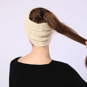 Detail view of beige knitted headband with ponytail hole and chunky texture