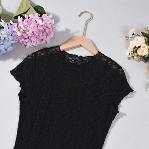 Detail of black floral lace top with round neck and short sleeves on a wooden hanger