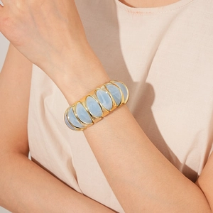 Detail of a vintage-style gold bracelet with light blue translucent cabochon stones on a wrist