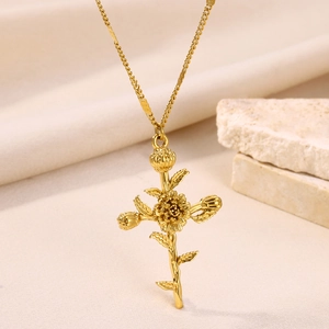 Macro detail of golden sunflower cross pendant on natural stone with fabric background