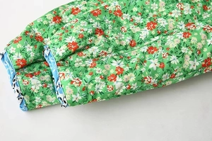 Detail of green floral quilted jacket showing red print and light blue trim finish