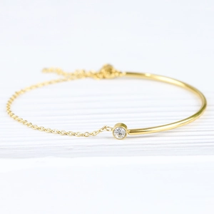 Macro shot of 18K gold-plated C-shaped stainless steel bracelet with zircon and chain detail